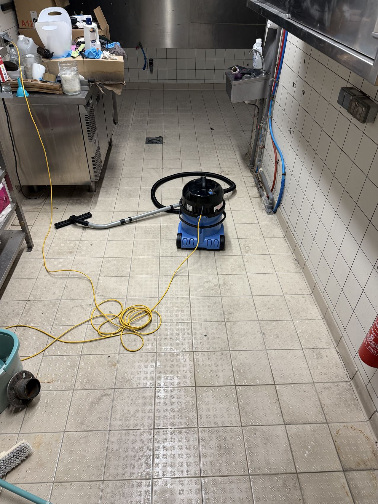 Cuisine de restaurant en cours de nettoyage, aspirateur professionnel au sol